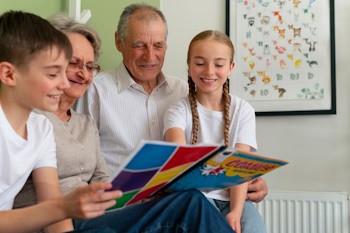 Abuelos leyendo un comic a sus dos nietos