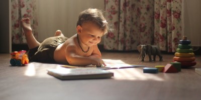 niño juega acostado en el piso con un libro y otros juguetes