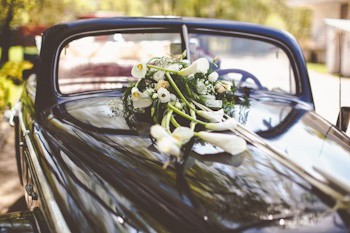 Coche de bodas negro decorado con flores