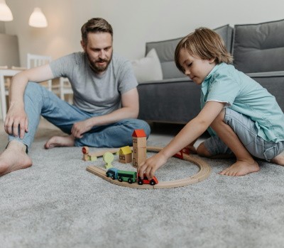padre e hijo juegan en el piso con un tren de madera