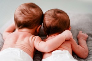 fotografía de dos bebés que están boca abajo y uno de ellos abraza al otro