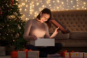 mujer bajo el árbol de Navidad abriendo un regalo
