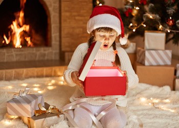 Niña sorprendida abriendo su regalo de Navidad en casa