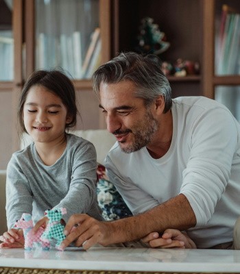 padre está sentado junto a su hija mientras juegan en la mesa