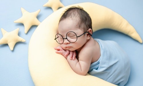 Bébé qui dort sur un oreiller en forme de lune : codes de réduction pour enfants sur bravopromo.fr