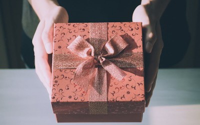 Manos que sostienen un regalo color rosa
