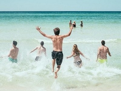 cinco personas están en la playa mientras una de ellas está saltando