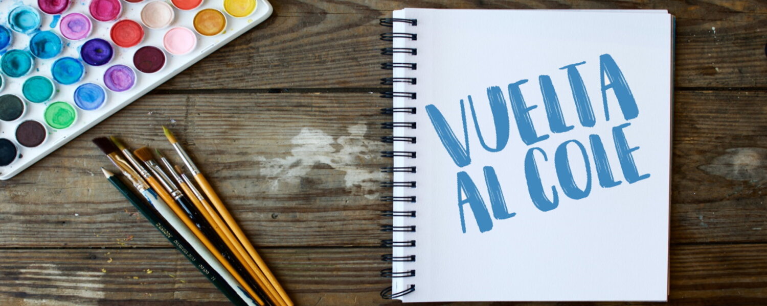 Cuaderno con portada donde pone "Vuelta al cole" junto a pinceles y colores