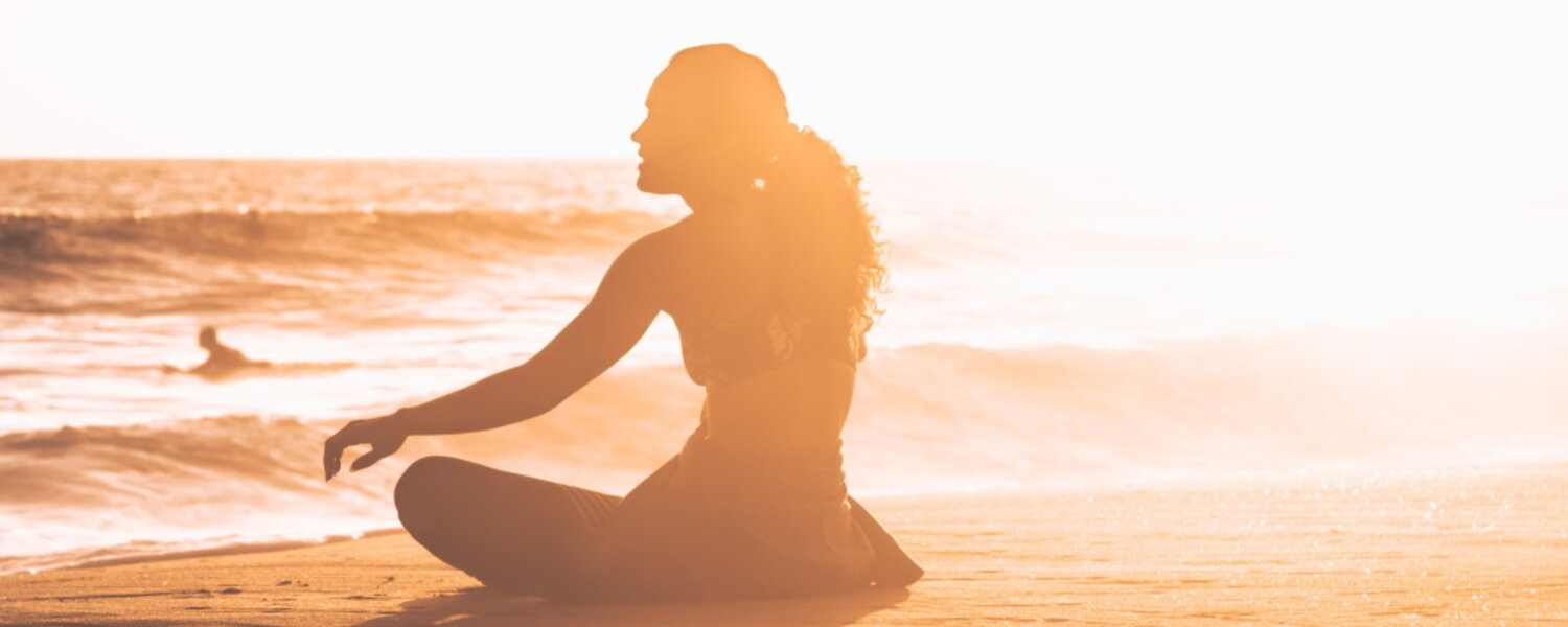 a woman sitting alone on the beach looking out at the ocean waves
