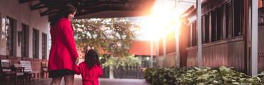 Mujer y su hija pequeña vestidas de rojo y cogidas de la mano paseando