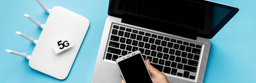 Portátil sobre una mesa, con aparato wifi 5G y celular de chica