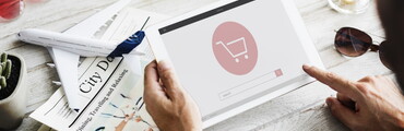 Manos de hombre sujetando una tablet con el símbolo de un carrito en la pantalla