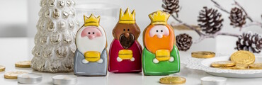 Figuritas de los tres reyes magos encima de una mesa, con decoración de monedas, piñas y árbol de navidad, todo en miniatura