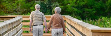 Hombre y mujer mayores caminando cogidos de la mano en la naturaleza