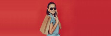 girl wearing sunglasses talking on the phone while holding a shopping bag