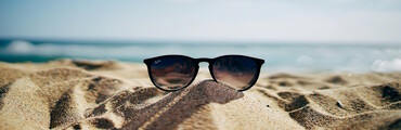 eine Ray-Ban Sonnenbrille an einem Sandstrand