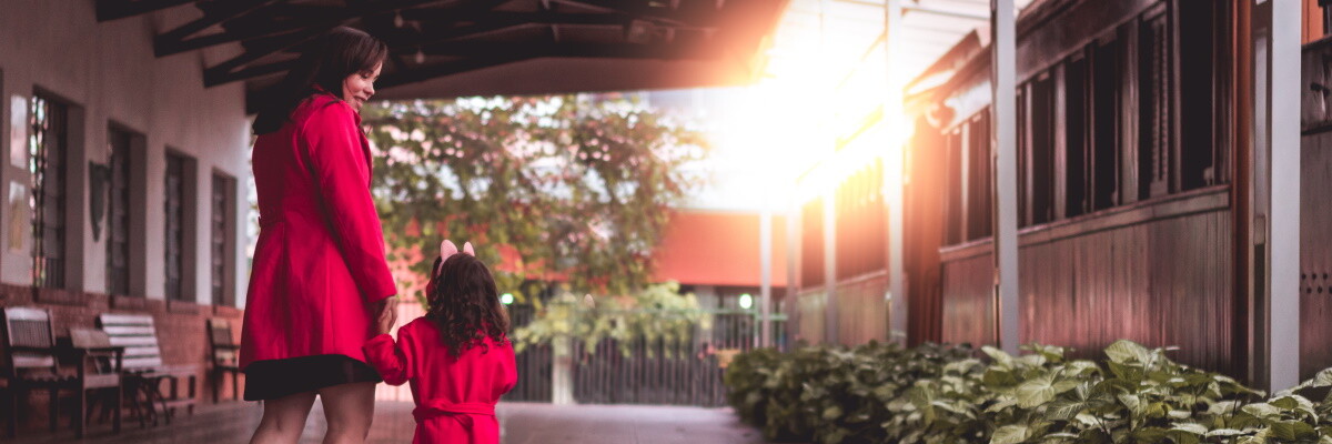 Mujer y su hija pequeña vestidas de rojo y cogidas de la mano paseando