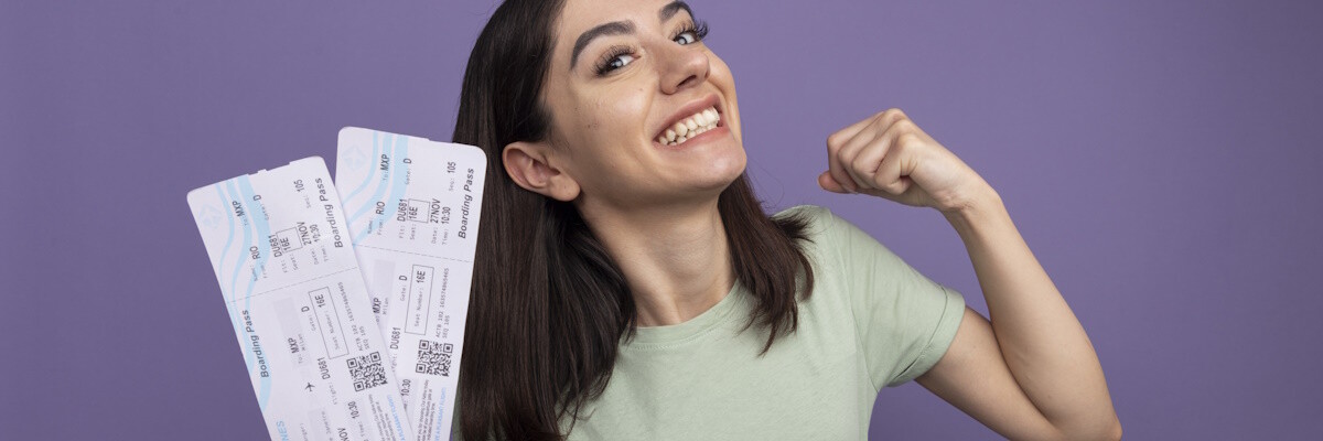 Chica feliz sujetando dos boletos de viaje