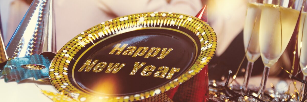 a party dish with Happy New Year in the middle surrounded by champagne glasses and party accessories