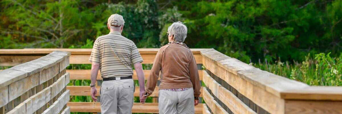 Hombre y mujer mayores caminando cogidos de la mano en la naturaleza