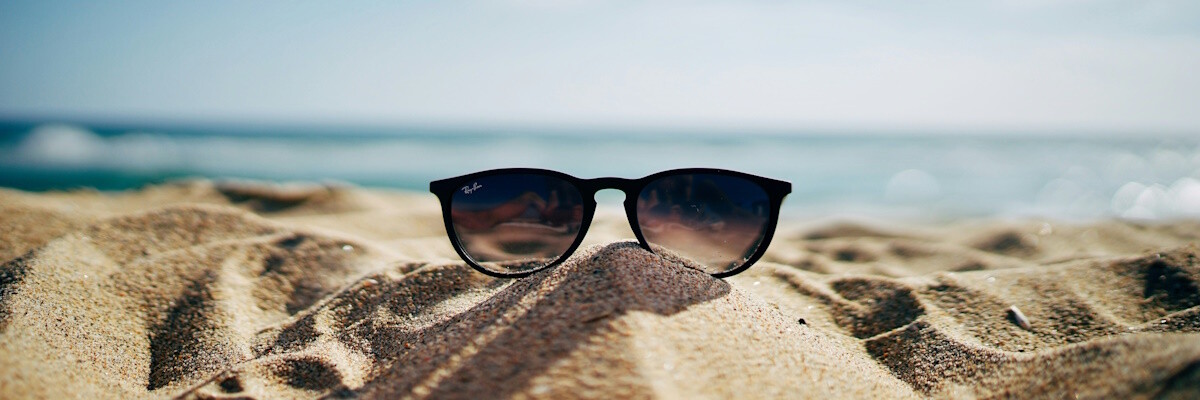 eine Ray-Ban Sonnenbrille an einem Sandstrand