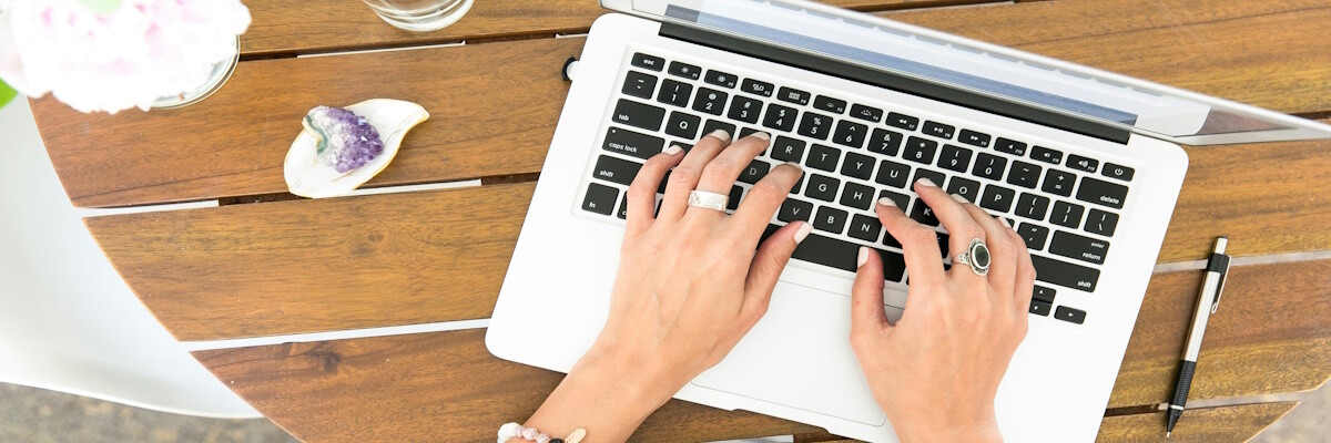Junge Frau arbeitet als Influencerin am Laptop – Fokus auf Hände und Tastatur.
