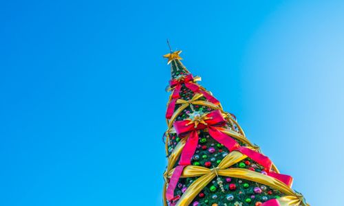 Ofertas de Natal para poupar em compras online! Céu azul no fundo com árvore de Natal como foco principal