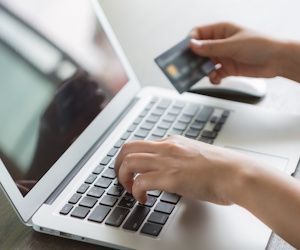 Pc portatil con manos de comprador y tarjeta en mano