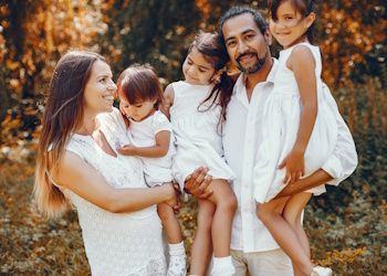 Padre, madre y tres hijas posando para una foto en la naturaleza