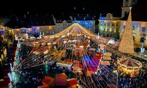 Não percas as ofertas de Natal! Foto de um mercado de Natal em uma praça Portuguesa com luzes e árvore de Natal