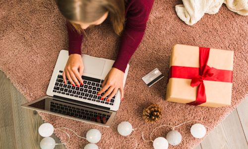 Aproveite as compras online durante o Natal! Mulher está a fazer compras online por usar seu laptop
