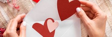 Sobre blanco con manos de mujer que introduce corazones de colores