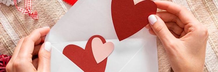 Sobre blanco con manos de mujer que introduce corazones de colores