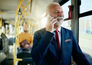 Señor mayor hablando por teléfono mientras viaja en autobús