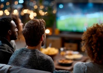Personas viendo la tele con comida en la mesa