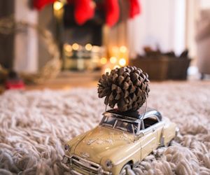 Maqueta de coche con piña navideña en el capo y chimenea decorada de navidad detras