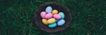ein Nest mit bunten Ostereiern auf Gras