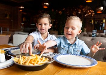 Dos hermanos comiendo patatas fritas en un restaurante