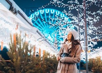Los mejores descuentos en mercados navideños Chica en un mercado navideño con la nieve y una noria detrás