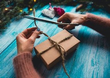 Ofertas en regalos navideños Mesa con manos femeninas que envuelven un regalo