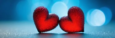 Dos corazones rojos sobre fondo azul que se apoyan el uno sobre el otro 