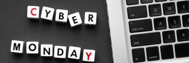 Svarta kuber som bildar texten Cyber Monday, bredvid en dator