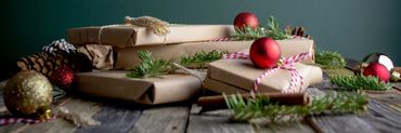 mesa llena de regalos de Navidad, esferas, canela y pedazos de pino