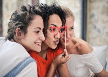Tres amigas haciéndose un selfie con unas gafas en forma de corazón Significado de San Valentín